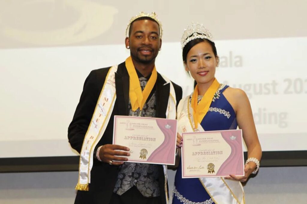 Aarro Loggins with sash and certificate for Mister Deaf International, poses with Miss Deaf International