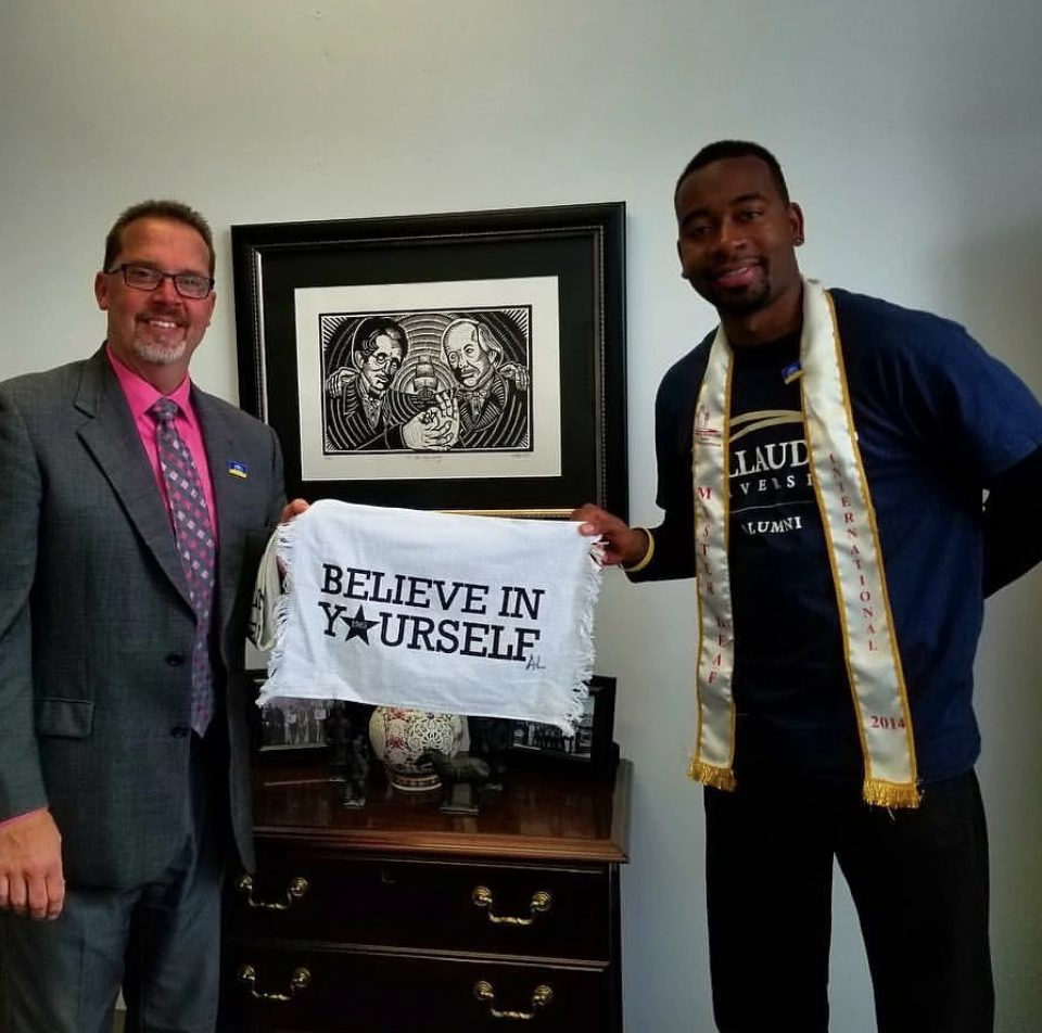 Aarron Loggins standing with a believe in yourself sign