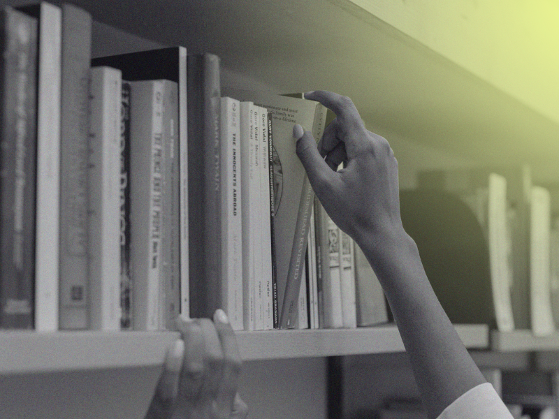person picking book off of bookshelf